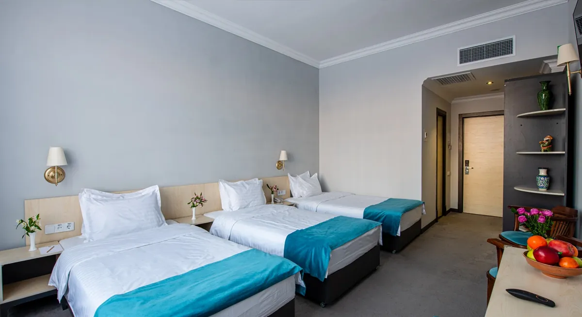 A hotel room arranged with an extra bed, warm and inviting, Khiva Residence Hotel